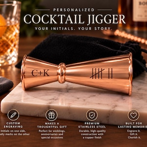 May include: A copper-finished cocktail jigger featuring custom engraving. One side displays the initials C+K, while the other side features seven tally marks. The double-ended measuring tool has a polished metallic surface and a central ring.