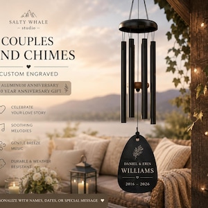 May include: Black metal wind chimes featuring five cylindrical tubes and a central wooden striker. A teardrop-shaped black wind catcher is engraved with the text DANIEL & ERIN WILLIAMS 2016-2026 and a floral sprig. The text COUPLES WIND CHIMES is visible.