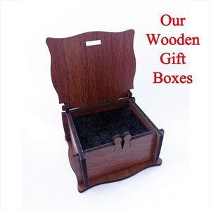 May include: A small, wooden gift box with a hinged lid. The box is made of dark brown wood and has a black velvet lining. The lid is open, revealing the empty interior of the box. The text "Our Wooden Gift Boxes" is printed in red letters on a white background.