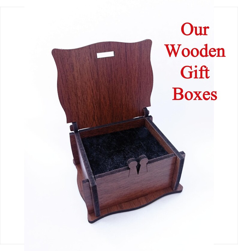 May include: A small, wooden gift box with a hinged lid. The box is made of dark brown wood and has a black velvet lining. The lid is open, revealing the empty interior of the box. The text "Our Wooden Gift Boxes" is printed in red letters on a white background.