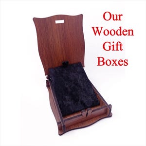 Pu&ograve; includere: Una scatola regalo in legno con un coperchio incernierato e un interno in velluto nero. La scatola &egrave; chiusa e il coperchio &egrave; aperto, rivelando l'interno in velluto. Il testo "Our Wooden Gift Boxes" &egrave; scritto in lettere rosse su sfondo bianco.