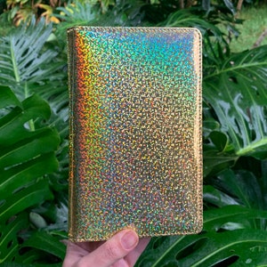 May include: A gold iridescent notebook cover with a glittery finish.