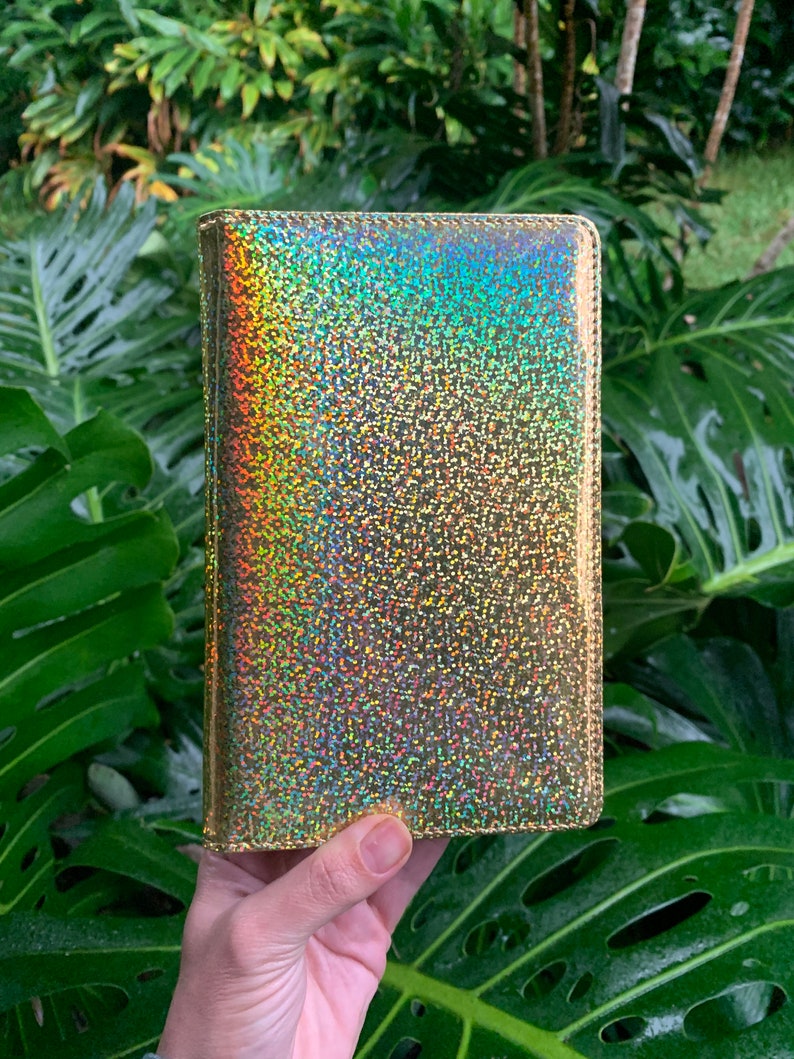 May include: A gold iridescent notebook cover with a glittery finish.