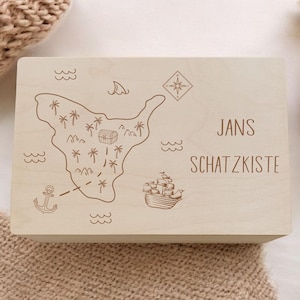 Könnte beinhalten: Eine hellfarbene Holzkiste mit einem Schatzkarten-Design. Die Karte zeigt eine Insel mit Palmen, eine Schatzkiste, einen Anker, ein Schiff und den Text "JANS SCHATZKISTE".