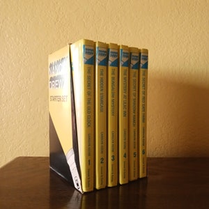 May include: A collection of Nancy Drew mystery books, including "The Secret of the Old Clock" and "The Hidden Staircase." The books have yellow spines with blue and white accents. The set is labeled "Starter Set."