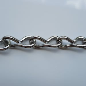 May include: A close-up of a silver chain with a hook on one end. The chain is made of interlocking links that are curved and smooth.