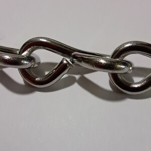 May include: A close-up of a silver chain with a broken link. The chain is made of metal and has a smooth finish.