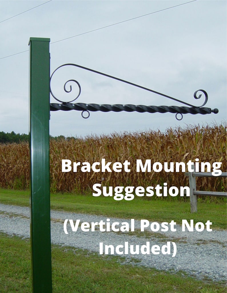 Op de afbeelding: Een donkergroene metalen beugel met een decoratieve gedraaide staaf en krulontwerp. De beugel is gemonteerd op een groene verticale paal. De tekst op de afbeelding luidt "Bracket Mounting Suggestion (Vertical Post Not Included)".