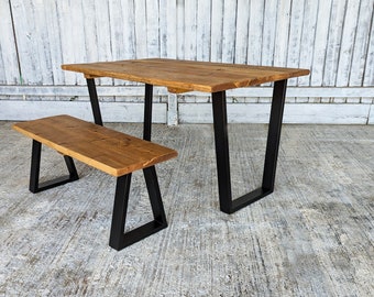 May include: A rustic wooden table and bench set with black metal legs. The table top is made of reclaimed wood and has a natural finish. The bench is also made of reclaimed wood and has a natural finish.
