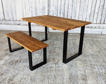 May include: A rustic wooden table and bench set with black metal legs. The table top is made of reclaimed wood and has a natural finish. The bench is also made of reclaimed wood and has a natural finish.