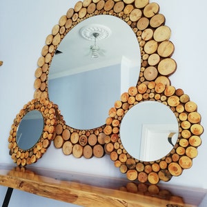May include: A set of three round mirrors with wooden log slice frames. The largest mirror is in the center, with a smaller one on each side. The mirrors are displayed on a wooden console table.