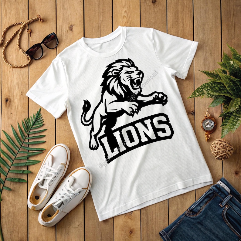 May include: White t-shirt featuring a black lion graphic and the word "LIONS". The image includes white trainers, sunglasses, and blue jeans on a wooden surface. A watch and decorative plant are also visible.
