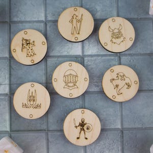 Puede incluir: Fichas de juego de madera con diseños de personajes de fantasía grabados, incluyendo un mago, un caballero y un esqueleto. Las fichas redondas tienen pequeños agujeros y están dispuestas sobre una superficie embaldosada con dados.