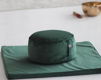 Puede incluir: Un cojín de meditación verde oscuro con una cremallera en el lateral, sentado sobre un cojín cuadrado verde oscuro.