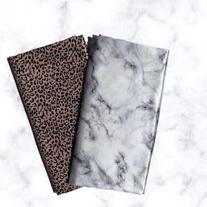 May include: Two fabric swatches, one with a brown and black leopard print and the other with a white and gray marble pattern.