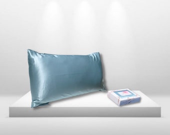 May include: A light blue satin pillowcase on a white surface with a small white box with a pink floral design.