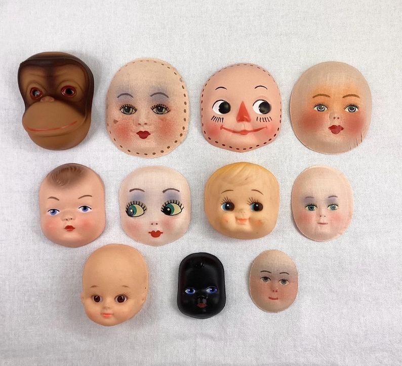 May include: Assortment of 10 doll face blanks, including a monkey face, a black face, and 8 different human faces. The faces are made of paper mache and are ready to be painted.