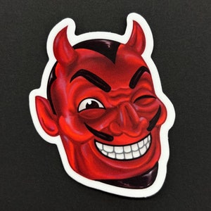 May include: A red devil face with horns, a mischievous grin, and a winking eye. The devil is depicted in a cartoon style with a white outline.