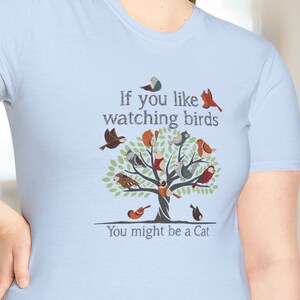 Puede incluir: Camiseta azul claro con un gr&aacute;fico de un &aacute;rbol con p&aacute;jaros y el texto "Si te gusta observar p&aacute;jaros, puede que seas un gato."