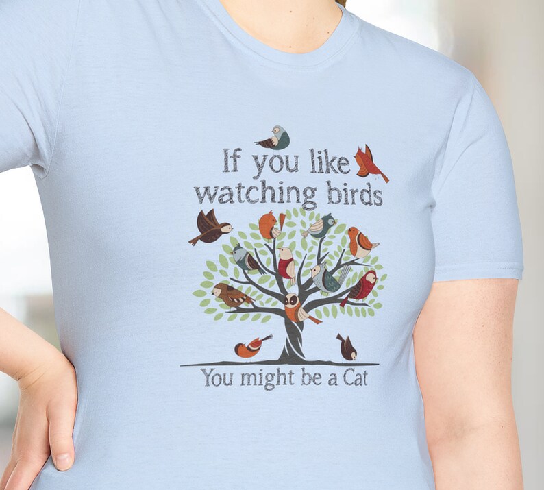Puede incluir: Camiseta azul claro con un gr&aacute;fico de un &aacute;rbol con p&aacute;jaros y el texto "Si te gusta observar p&aacute;jaros, puede que seas un gato."