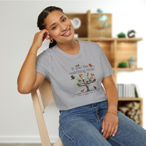 Puede incluir: Una camiseta gris con un gr&aacute;fico de un &aacute;rbol con p&aacute;jaros en &eacute;l. El texto en la camiseta dice "If you like watching birds You might be a Cat."