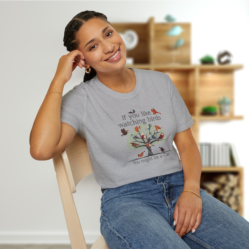 Puede incluir: Una camiseta gris con un gr&aacute;fico de un &aacute;rbol con p&aacute;jaros en &eacute;l. El texto en la camiseta dice "If you like watching birds You might be a Cat."