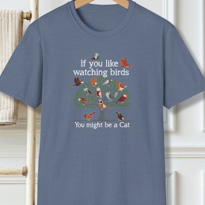 Puede incluir: Una camiseta azul con un gr&aacute;fico blanco de un &aacute;rbol con p&aacute;jaros y el texto "Si te gusta observar p&aacute;jaros Puede que seas un gato".