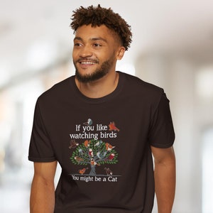 Puede incluir: Una camiseta marr&oacute;n con un gr&aacute;fico de un &aacute;rbol con p&aacute;jaros y el texto "Si te gusta observar p&aacute;jaros Puede que seas un gato."