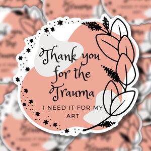 Peut inclure: Un autocollant rose et blanc avec du texte noir et un motif floral noir. Le texte dit "Merci pour le traumatisme, j'en ai besoin pour mon art."
