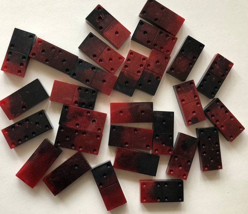 May include: A collection of red and black dominoes. The dominoes are made of a smooth, glossy material.