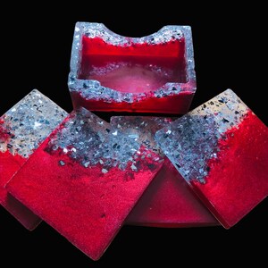 Könnte beinhalten: Satz mit vier roten und silbernen Glitzer-Untersetzern mit einem passenden roten und silbernen Glitzer-Tablett. Die Untersetzer und das Tablett haben eine glitzernde, irisierende Oberfläche.