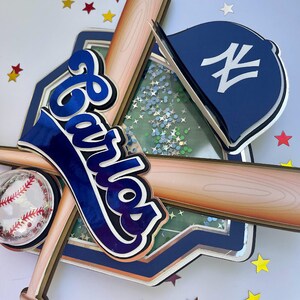 Pu&ograve; includere: Un topper per torta a strati a tema baseball blu e bianco con il nome "Carlos" in un font corsivo blu e nero. Il topper include una mazza da baseball, una palla da baseball, un cappello da baseball e un campo da baseball.