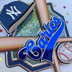 Pu&ograve; includere: Un cappello da baseball blu e bianco con il logo dei New York Yankees, uno striscione con il nome di baseball blu con il nome "Carlos", due mazze da baseball di legno e una palla da baseball di plastica trasparente con cuciture rosse.