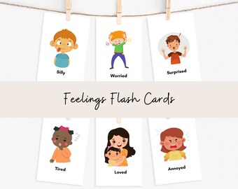 May include: Set of six illustrated flash cards featuring different emotions. The cards are white with colorful cartoon characters depicting feelings such as silly, worried, surprised, tired, loved, and annoyed. The cards are hung on a string with clothespins.