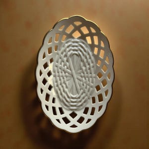May include: White oval-shaped ceramic basket with a lattice design and a gold trim. The basket has an open weave pattern, allowing light to pass through. The interior features a woven texture.