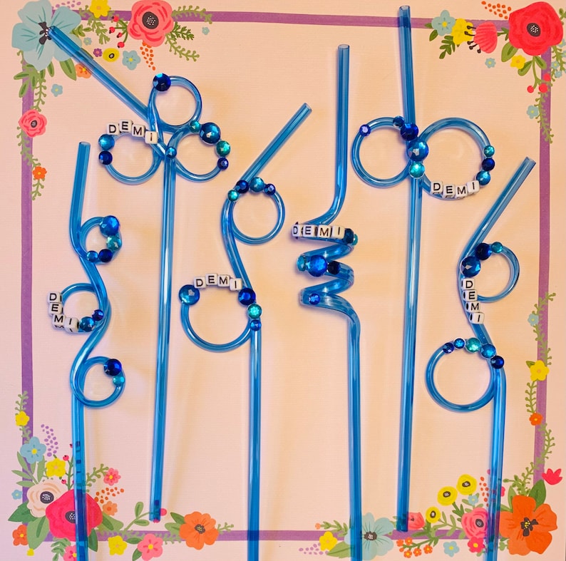 Puede incluir: Seis pajitas de pl&aacute;stico azules con cuentas de colores y la palabra "DEMI" escrita en cada pajita.