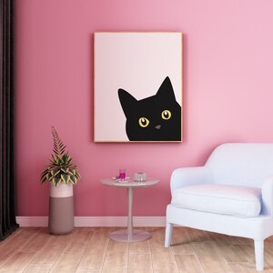 May include: A black cat with yellow eyes peeks out from a framed print hanging on a pink wall. A light blue armchair sits in front of a small round table with a glass top.