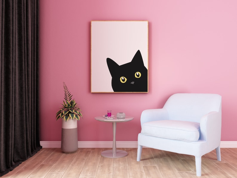 May include: A black cat with yellow eyes peeks out from a framed print hanging on a pink wall. A light blue armchair sits in front of a small round table with a glass top.