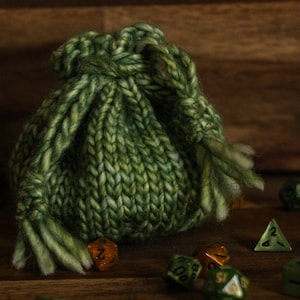 May include: A green knitted drawstring bag with a fringe, filled with green and gold dice.