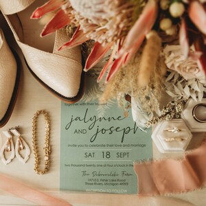 Pode incluir: Um convite de casamento com fundo azul claro e texto branco. O convite diz "jalynne e joseph convidam você a celebrar seu amor e casamento SÁB 18 SET dois mil e vinte e um às quatro na The Dobrowolaks Farm 197105 Feher Lake Road Three Rivers, Michigan 49093 RECEPÇÃO A SEGUIR". O convite é cercado por um buquê de flores rosa e vermelhas, uma pulseira de ouro, um par de brincos brancos e dois sapatos brancos.