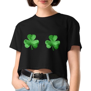 May include: Black crop top featuring two green watercolor shamrock designs. The shirt is a casual style, perfect for St. Patrick's Day or everyday wear. The shamrocks are a vibrant green, adding a pop of color to the black fabric.