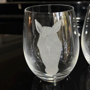 Puede incluir: Una copa de vino de vidrio transparente con un dise&ntilde;o grabado de una cabeza de caballo.