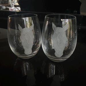 Puede incluir: Dos copas de vino de vidrio transparente con dise&ntilde;os de cabeza de caballo grabados.