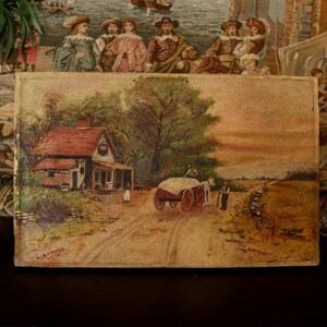 May include: An antique landscape painting showing a rural scene with a house, a horse-drawn cart, and figures on a dirt track. The artwork has warm tones and a vintage look, with a signature in the lower left corner.