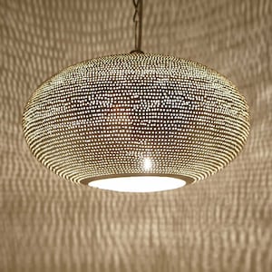 May include: A silver, round, hanging pendant light fixture with a perforated design. The light fixture has a white, round, frosted glass shade.