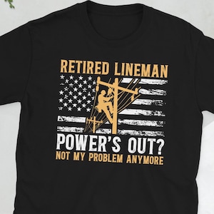 以下が含まれることがあります： 「RETIRED LINEMAN」の文字と、電線作業員のシルエットが入ったアメリカ国旗のデザインがプリントされた黒いTシャツ。「POWER'S OUT? NOT MY PROBLEM ANYMORE」の文字が下にあります。