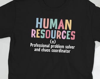 May include: Black t-shirt with the words "HUMAN RESOURCES" in pastel colors. Below the text is the definition: "Professional problem solver and chaos coordinator."