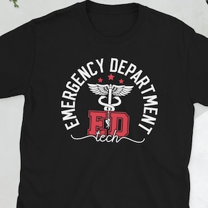 May include: Black t-shirt with a white and red graphic. The graphic reads "Emergency Department" in a circular design, with "ED tech" in the center. A caduceus symbol is in the center of the design.