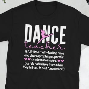 May include: Black t-shirt with the words "DANCE teacher" in white and pink. The shirt features a dancer graphic and text that reads "A full-time multi-tasking ninja and choreographing superstar who loves to inspire."