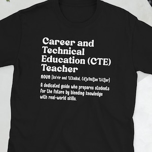 Könnte beinhalten: Ein schwarzes kurzärmeliges T-Shirt mit weißem Textaufdruck: Career and Technical Education (CTE) Teacher, noun, gefolgt von einer phonetischen Aussprache und der Definition: A dedicated guide who prepares students for the future by blending knowledge with real-world skills.